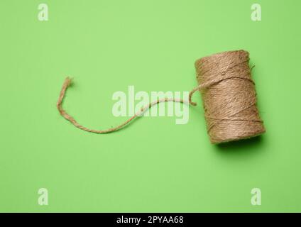 Brown thread spool on a green background, packaging rope Stock Photo