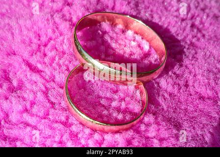 gold rings, male and female, on a pink shaggy background Stock Photo