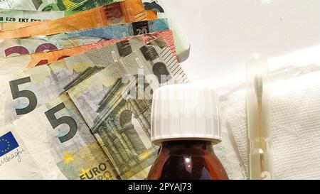 Euro paper notes. European currency on a white background close-up. A bottle of medicine and a measuring syringe next to money. The high cost of treatment. Bank notes for 5, 10, 20, 50 and 100 Stock Photo