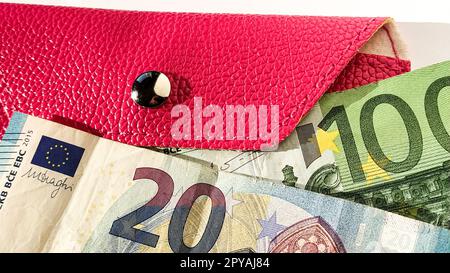Euro paper notes. European currency on a white background close-up. Wallet or purse in bright pink with a metallic shiny button. Banknotes of the Central Bank for 20 and 100 euros Stock Photo