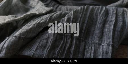 Gray pleated fabric or crumpled textile closeup. Light translucent curtains or tulle in the Scandinavian style. The lower edge of the curtain is hemmed 2-3 cm from the edge. Soft focus Stock Photo