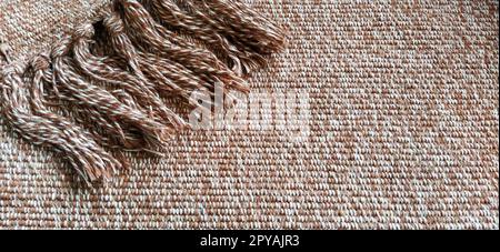 Woven fabric with tassels. Coarse weaving cotton. Floor mat. Beige, white and wrinkled threads in weaving. Woolen or acrylic material Stock Photo