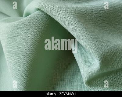 Close up of a woolen fabric of green color. Abstract canvas background, empty template. Thin natural fabric, wool or linen Stock Photo