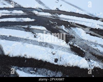 Snowdrifts on the side of the road. Bad weather and traffic. Snow on asphalt. Difficult driving conditions. Winter slosh on the road. Braking distance of a car. Stock Photo