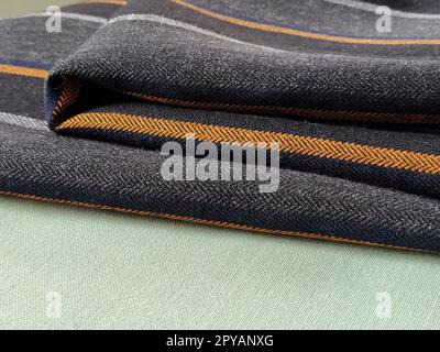 Light green and black-gray folded fabric with orange and dark blue stripes. Interior decoration. Dress fabrics in casual style. Dense material for indoor curtains and furniture finishing Stock Photo