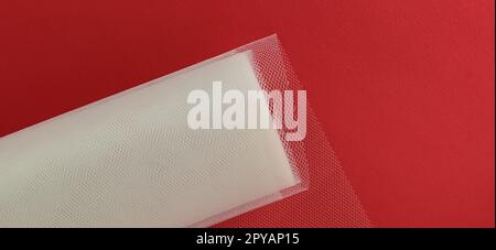 Fabric - white mesh in a roll on a red background. Nylon tape for tying bows on hair. A skein of tulle fabric. Copy space Stock Photo