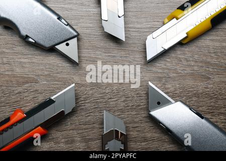 Many different utility knives on wooden table, flat lay Stock Photo