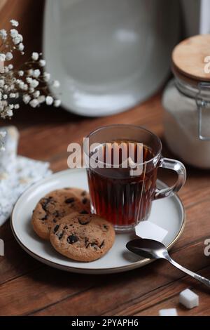 Cup of freshly brewed tea and delicious cookies on wooden table Stock Photo