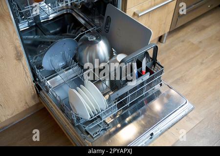 Stack of dirty dishes in dishwasher needs to be cleaned, open door with plates and dishes high angle view Stock Photo