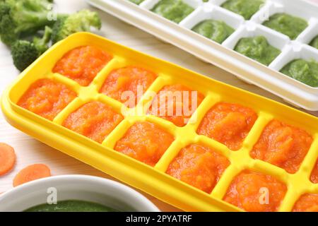 Purees in ice cube trays ready for freezing on white wooden table, closeup Stock Photo