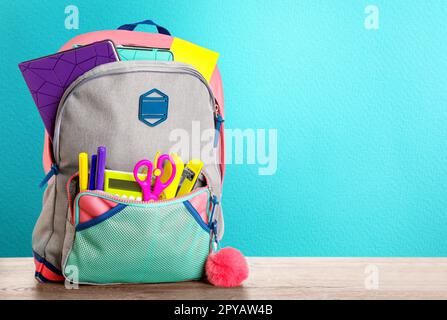 Backpack with school stationery on wooden table against light blue background, space for text Stock Photo