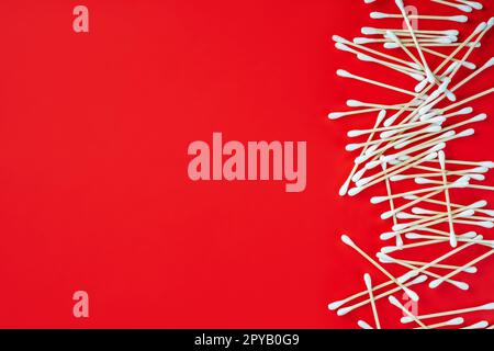 Wooden cotton buds on red background. Environmental conservation concept. Auricle hygiene. Copy space. Flat lay. Stock Photo
