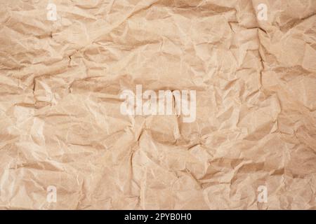 Background image of rough crumpled recycled textured kraft paper. Top view, copy space Stock Photo
