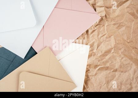 Background image of rough crumpled textured kraft paper with multi-colored cardboard envelopes. Top view. Copy space Stock Photo