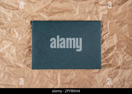 Background image crumpled recycled textured kraft paper with sheet of green cardboard in middle. Top view. Copy space Stock Photo