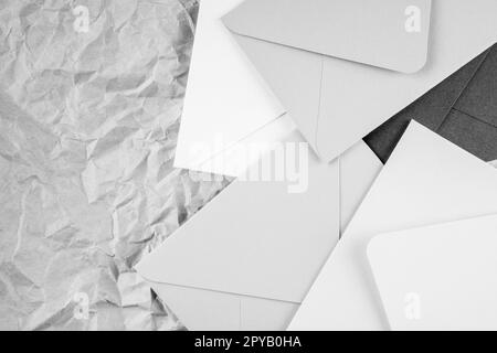 Background image of black white cardboard envelopes lying randomly on crumpled paper background. Top view. Copy space Stock Photo