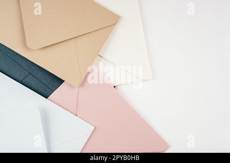 Background image of multi-colored cardboard envelopes lying randomly on white background. Top view, copy space Stock Photo