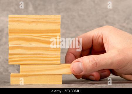 Hand pulling out wooden block from a tower Stock Photo