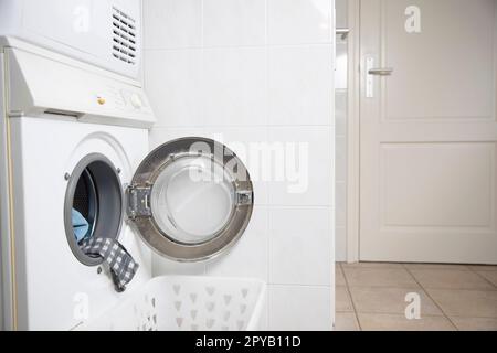 Laundry concept. white and modern washing machine with open door standing inside bright apartment or house light interior close up Stock Photo