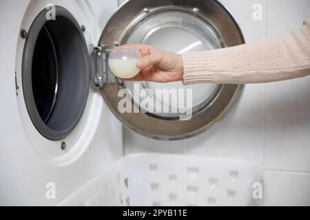 Closeup of liquid gel detergent pouring from the spout of a plastic bottle  into a measuring cup, with dirty washing / laundry in the background Stock  Photo - Alamy