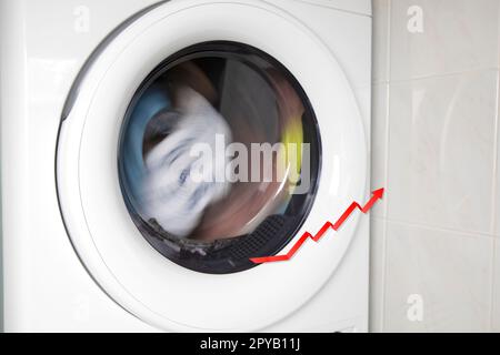 Concept of saving electricity with a washing machine white electrical power strip and red arrow up. Stock Photo