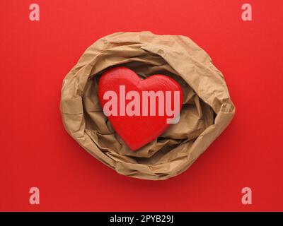 Wooden Heart decoration on crumpled beige paper and red paper background Stock Photo