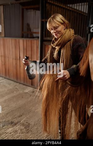 Horse owner spraying stallion with conditioner during grooming and cleaning Stock Photo