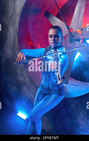 Young woman playing electronic violin in neon glowing light Stock Photo