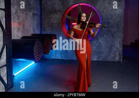 Beautiful woman playing violin concert against industrial background Stock Photo