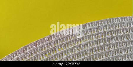 Straw hat on a yellow background. The edge of the wide brim of the hat. Weave threads or twigs. Close-up. Summer holiday theme Stock Photo