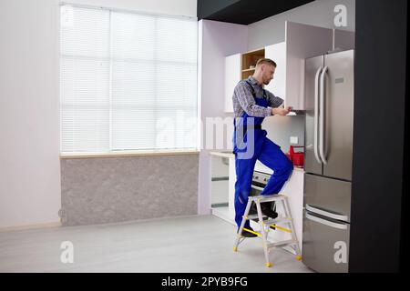 Male Carpenter Assembling White Cabinet On Wall Stock Photo