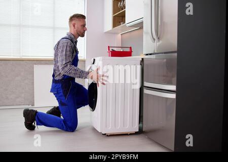 Young Man In Overall Repairing Washing Stock Photo