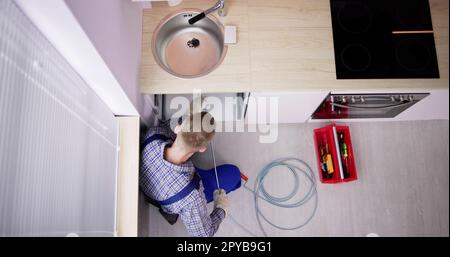 Plumber Drain Cleaning Services In Kitchen Stock Photo