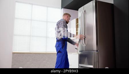 Male Worker Repairing Refrigerator With Screwdriver Stock Photo