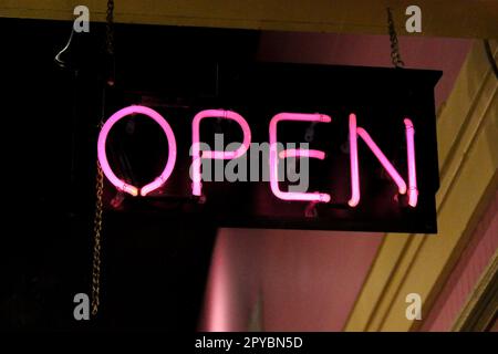 Open pink neon sign in a business window Stock Photo