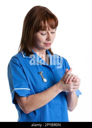 Health Professionals: Clean Hands. A uniformed medical nurse sterilising her hands. From a series of related images isolated on white. Stock Photo