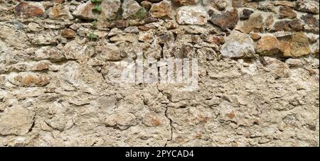 Stone wall. Stacked large cobblestones in warm colors. A crack in the middle of the old masonry. Tower in Kula, Serbia. Stock Photo