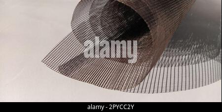 Roll of window screen, closeup. Roll of brown mosquito nets. Barrage mesh. Grid on white background Stock Photo