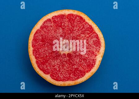 Sliced side of a grapefruit with red pulp isolated on a blue background Stock Photo