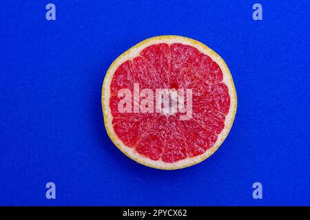 Sliced side of a grapefruit with red pulp isolated on a blue background Stock Photo