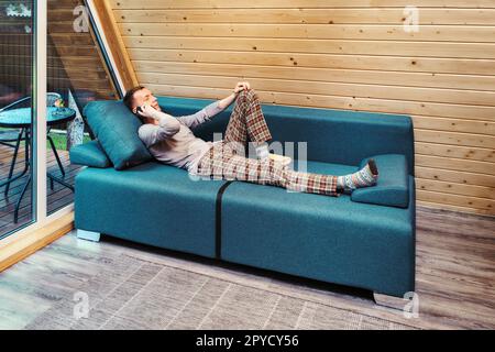 Middle aged man talking on the phone while resting in his forest cabin on vacations Stock Photo