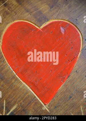 The shape of a heart carved with a knife on a wooden surface and painted in a bright red. A symbol of love and fidelity. Postcard or picture for congratulations or confessions on Valentines Day. Stock Photo