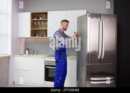 Male Worker Repairing Refrigerator With Screwdriver Stock Photo