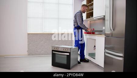 Young Repairman Installing Induction Cooker Stock Photo