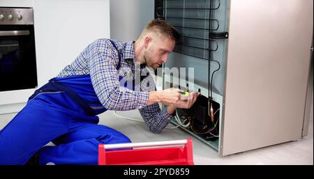 Cropped Image Of Serviceman Working On Fridge With Screwdriver Stock Photo