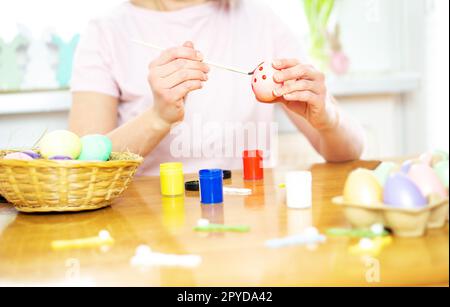 Close up of female hands holding Easter egg and painting with a paintbrush. Preparation to Easter. Stock Photo