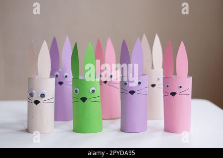 A banner from handmade easter bunny toy gift on a white table background. Many paper easter rabbits made from toilet paper rolls. Happy easter. High quality photo. Stock Photo