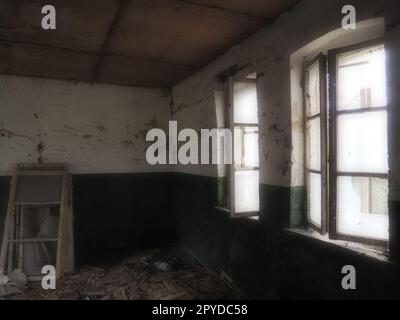 Scary windows. Inside an abandoned house. View of broken windows without a curtain. Grunge scene. Light shines through old wooden frames with broken glass. The concept of abandonment and uselessness Stock Photo