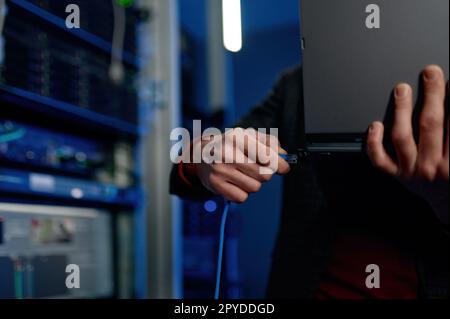 IT technician switching wire to laptop computer closeup Stock Photo