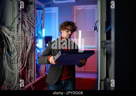 Portrait of it specialist holding hardware in hand standing in server room Stock Photo